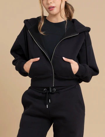 Woman wears black hoodie with hands in the pockets